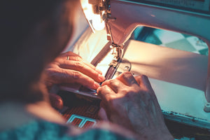Fairly treated factory worker stitching bags on sewing machine 